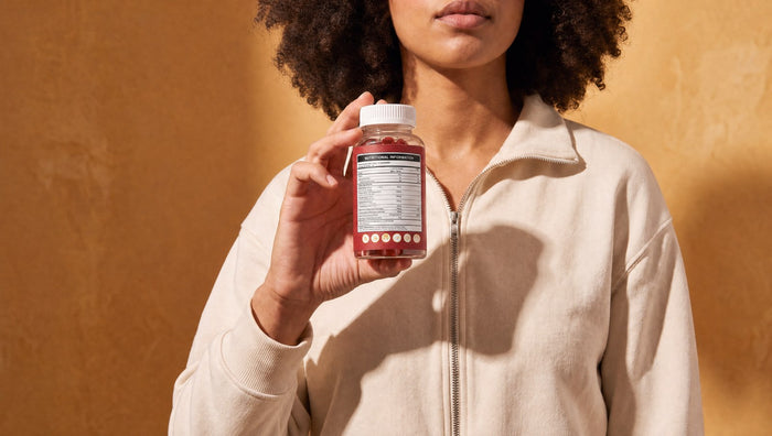 Woman reading the back label of a Healthier Options supplement bottle