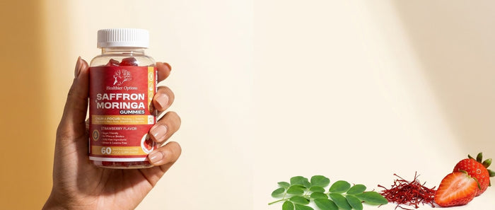 Hand holding Healthier Options gummies with fresh moringa leaves and strawberries