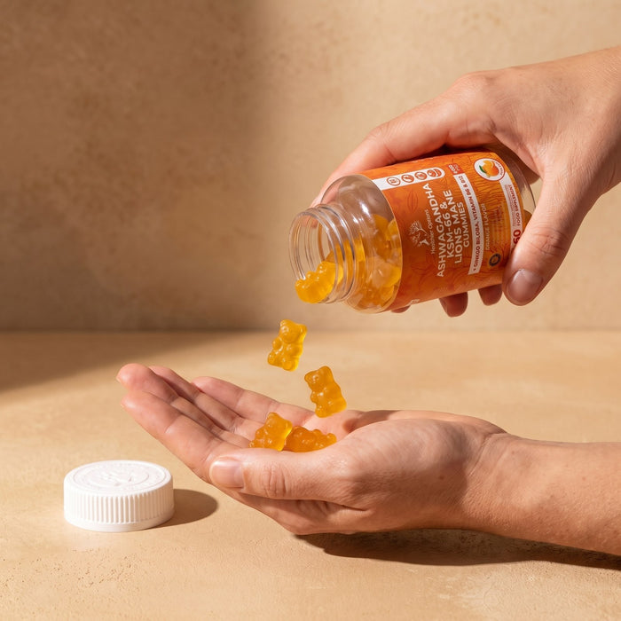 Hands pouring orange Ashwagandha gummies from the bottle