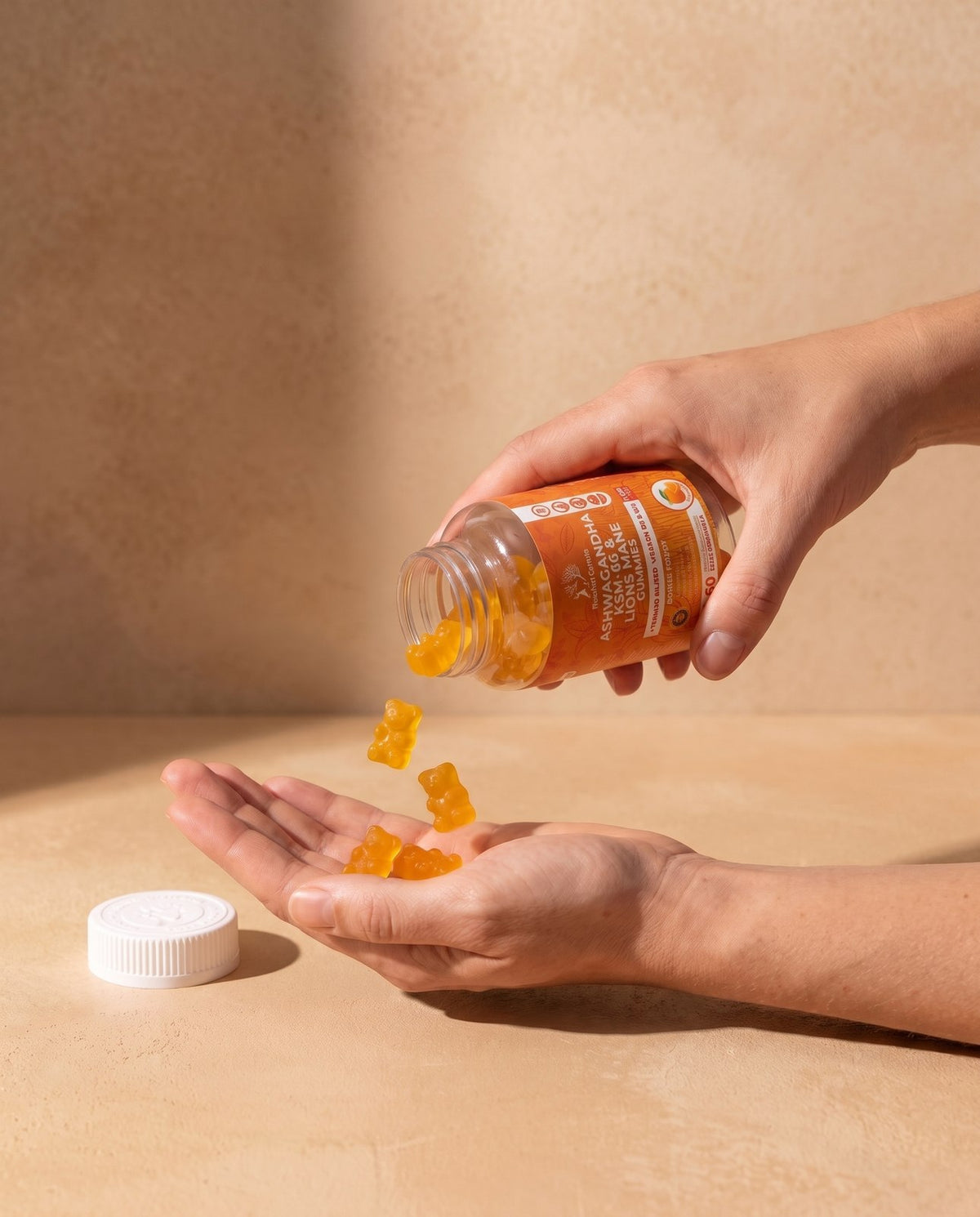 Orange flavour Ashwagandha gummies poured from the bottle into a hand